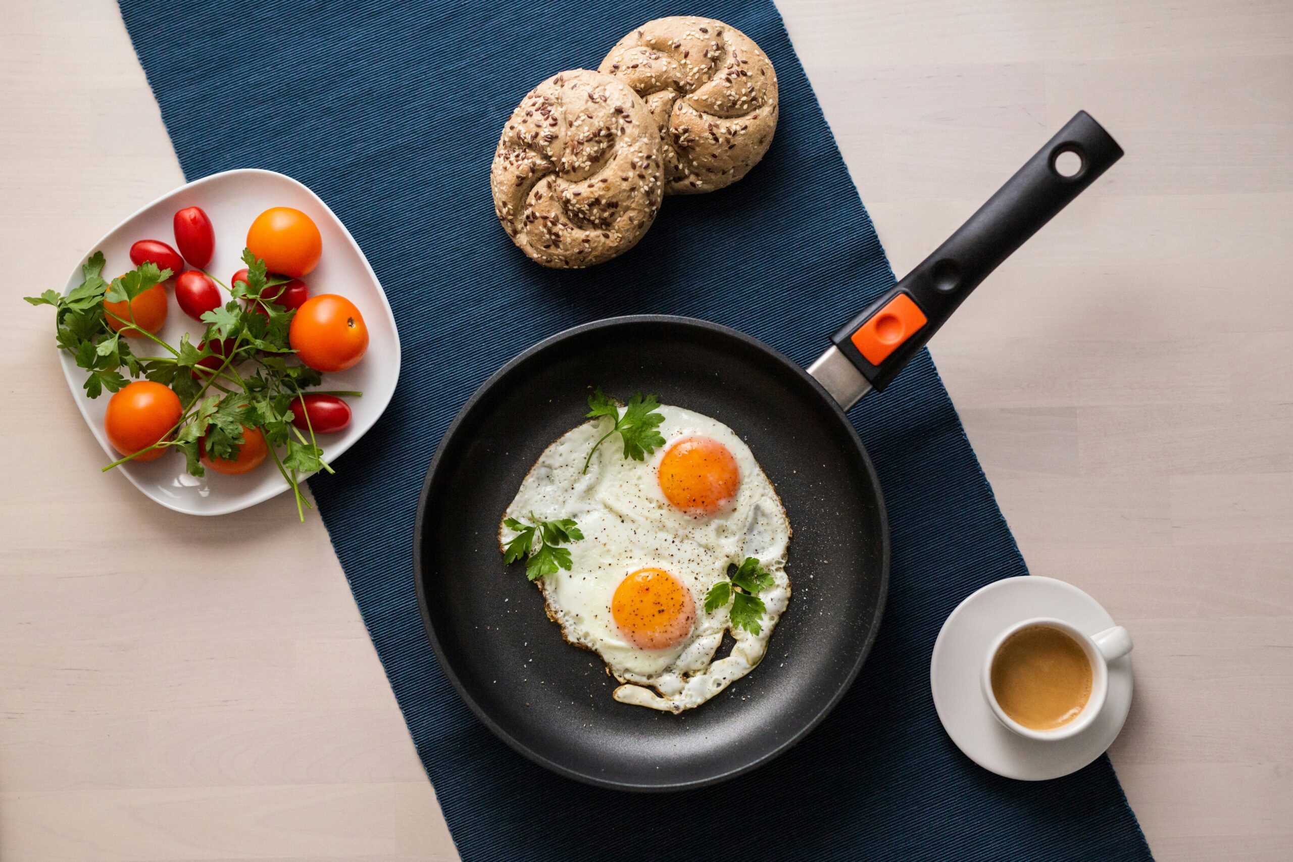 Chalkboard sign with the text "Keto Breakfast Ideas for Beginners" surrounded by keto-friendly foods like avocado, eggs, bacon, nuts, yogurt, and low-carb pancakes